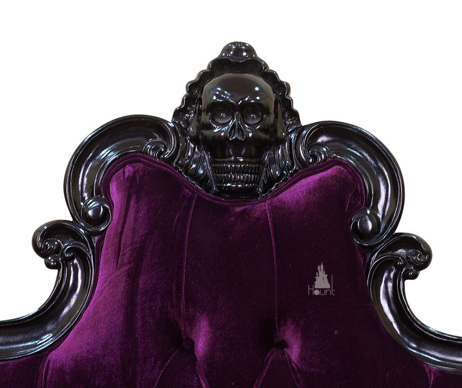 The Death Aphrodite Bed, a handcrafted upholstered gothic bed with a tall shaped headboard, curved footboard and a carved skull crest.