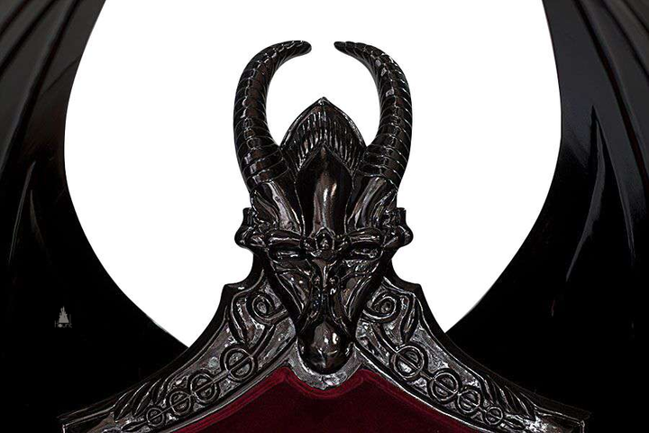 The House of Fire Throne, a handcrafted gothic throne chair with a bat-wing frame, horned carved crest and shield-shaped upholstered back.