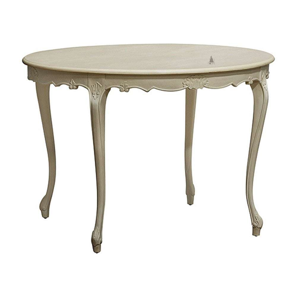 The Odyssey Dining Table, a handcrafted round dining table with a light-toned finish, carved apron and elegant curved legs.