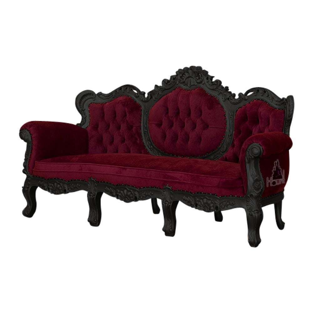 Seduce Lounge by Haunt Cult, a three-seat lounge in deep red velvet with three rounded button-tufted back panels, rolled arms, a dark carved frame and ornate crest carving across the top rail and apron
