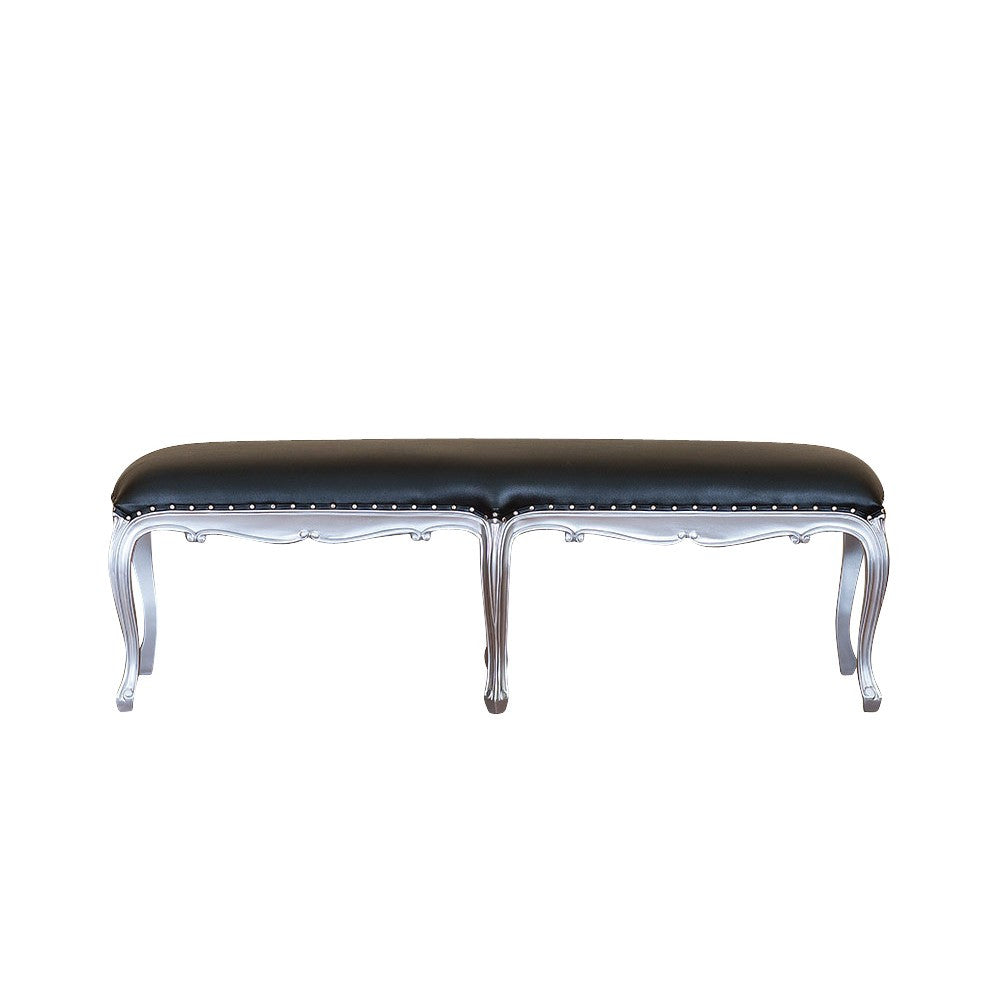 Luxe Bench, a long upholstered bench with a black tufted seat, a silver-toned carved frame and a row of slender turned legs